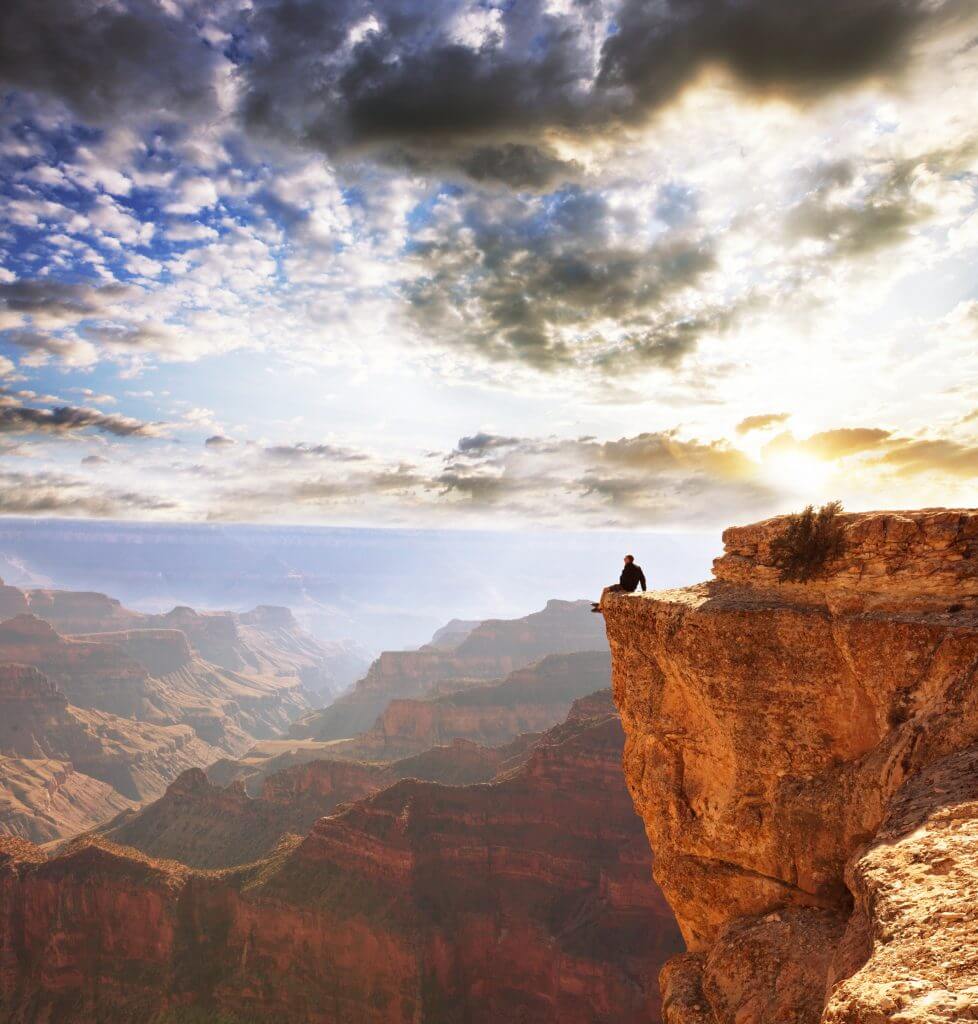 man sitting on the edge of the grand canyon